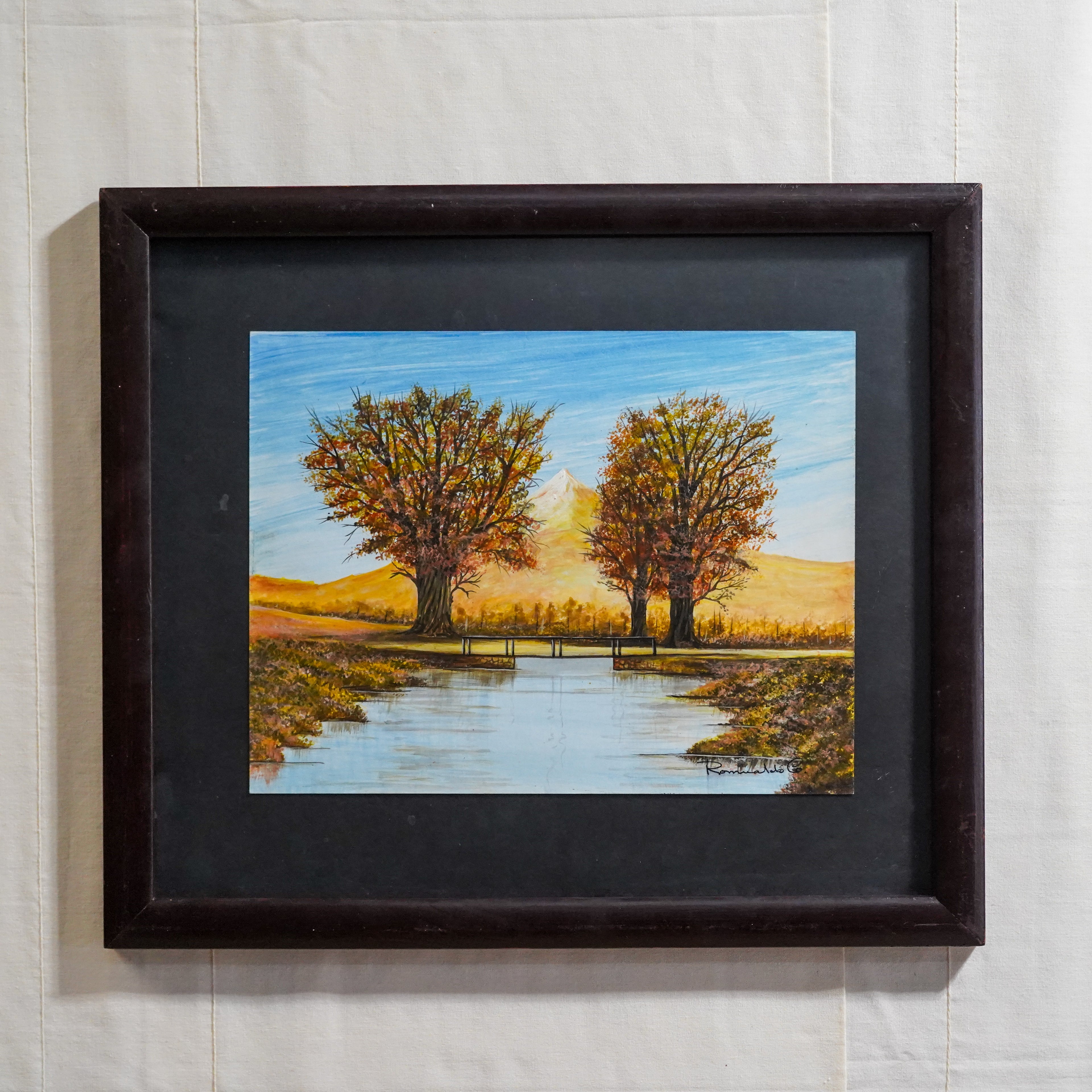 Pintura de paisaje de puente frente a dos árboles y montaña sobre río